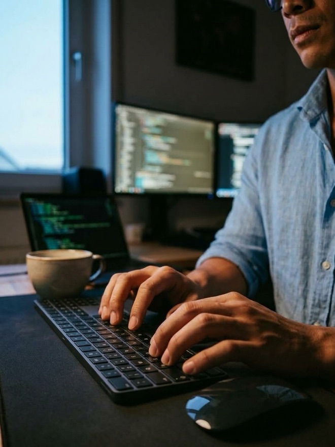 Entwicklung am Schreibtisch mit Code auf drei Bildschirmen